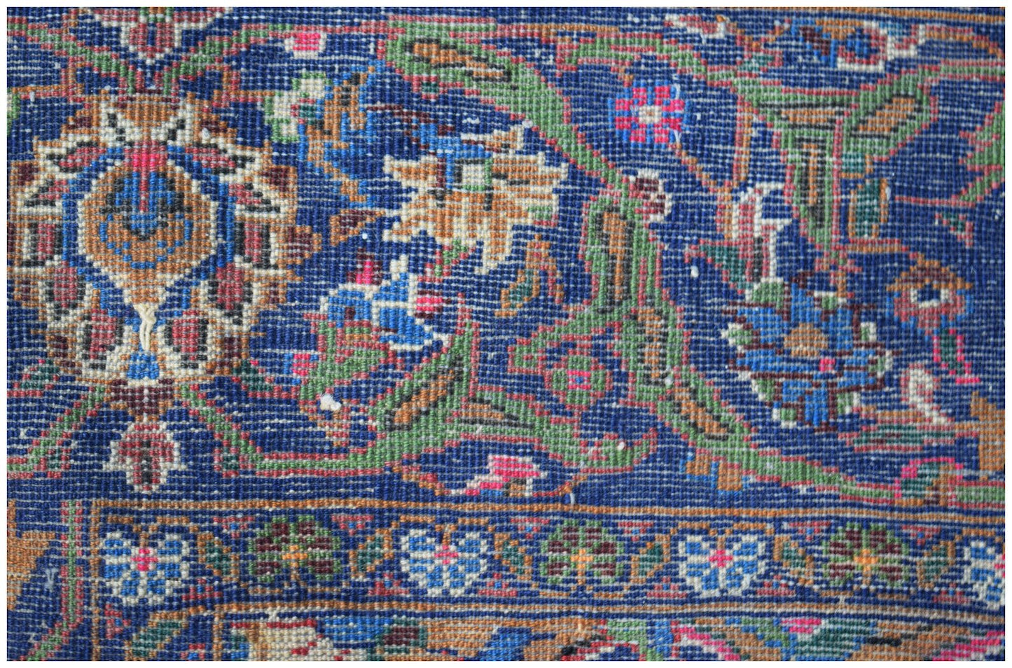 A close-up of a vintage Afghan Baluch rug featuring intricate floral patterns in blue and brown.