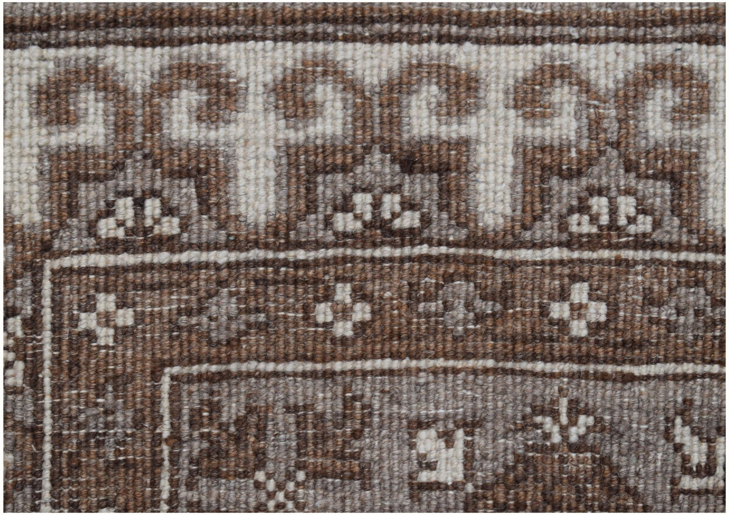 A close-up of a handmade Afghan Chobi runner featuring intricate brown and cream geometric patterns.