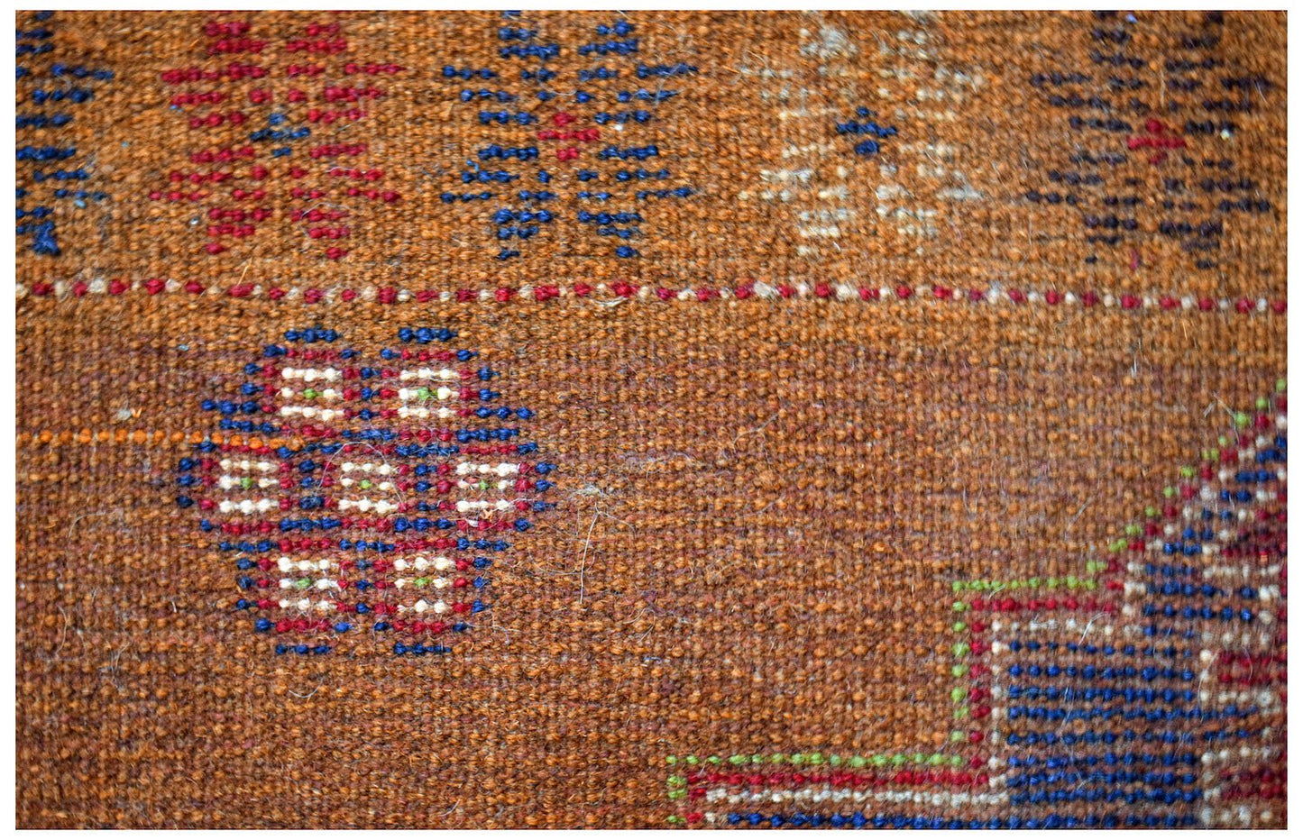A handmade Afghan Pashm rug featuring a brown wool base with geometric blue and red patterns.