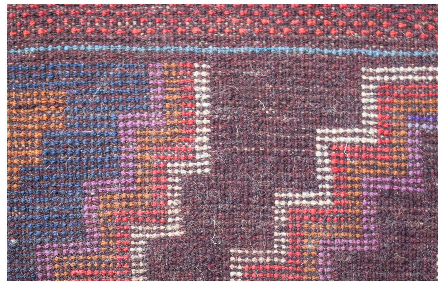 A handmade Afghan Pashm rug featuring a geometric stepped pattern in dark red, blue, and ivory.