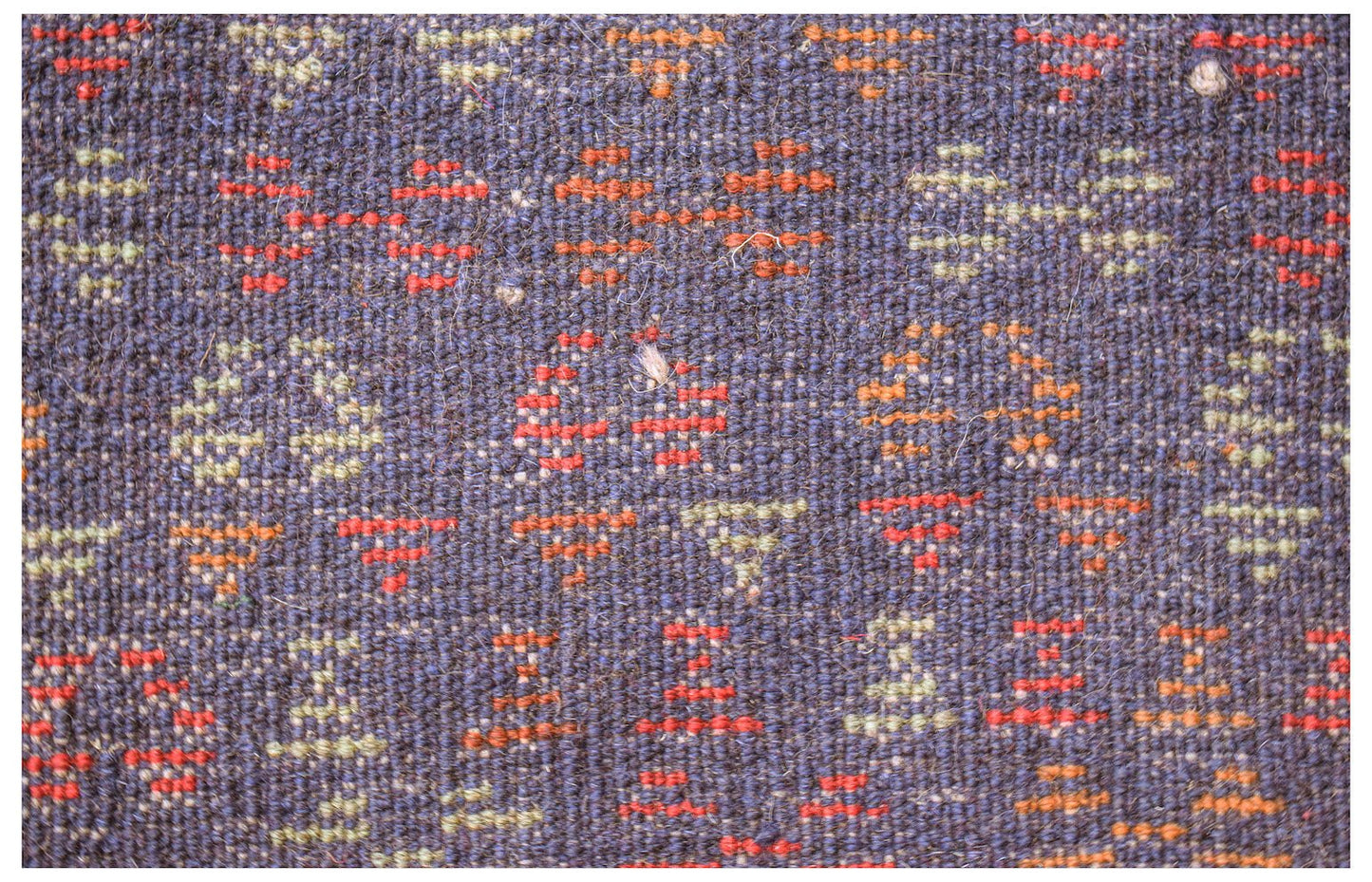 Handmade Afghan Pashm rug featuring a dark blue wool base with small geometric red and tan motifs.