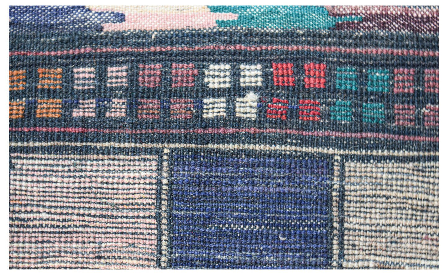 A close-up of a handmade Afghan wool rug featuring a geometric pattern of blue and ivory squares.