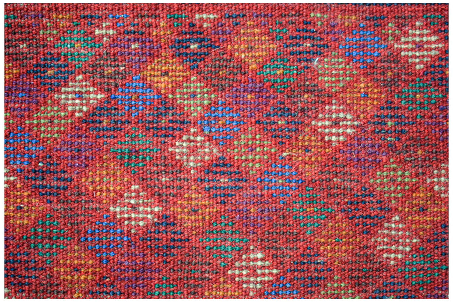 Handmade Afghan Pashm rug featuring a geometric diamond pattern in red, blue, and ivory wool.