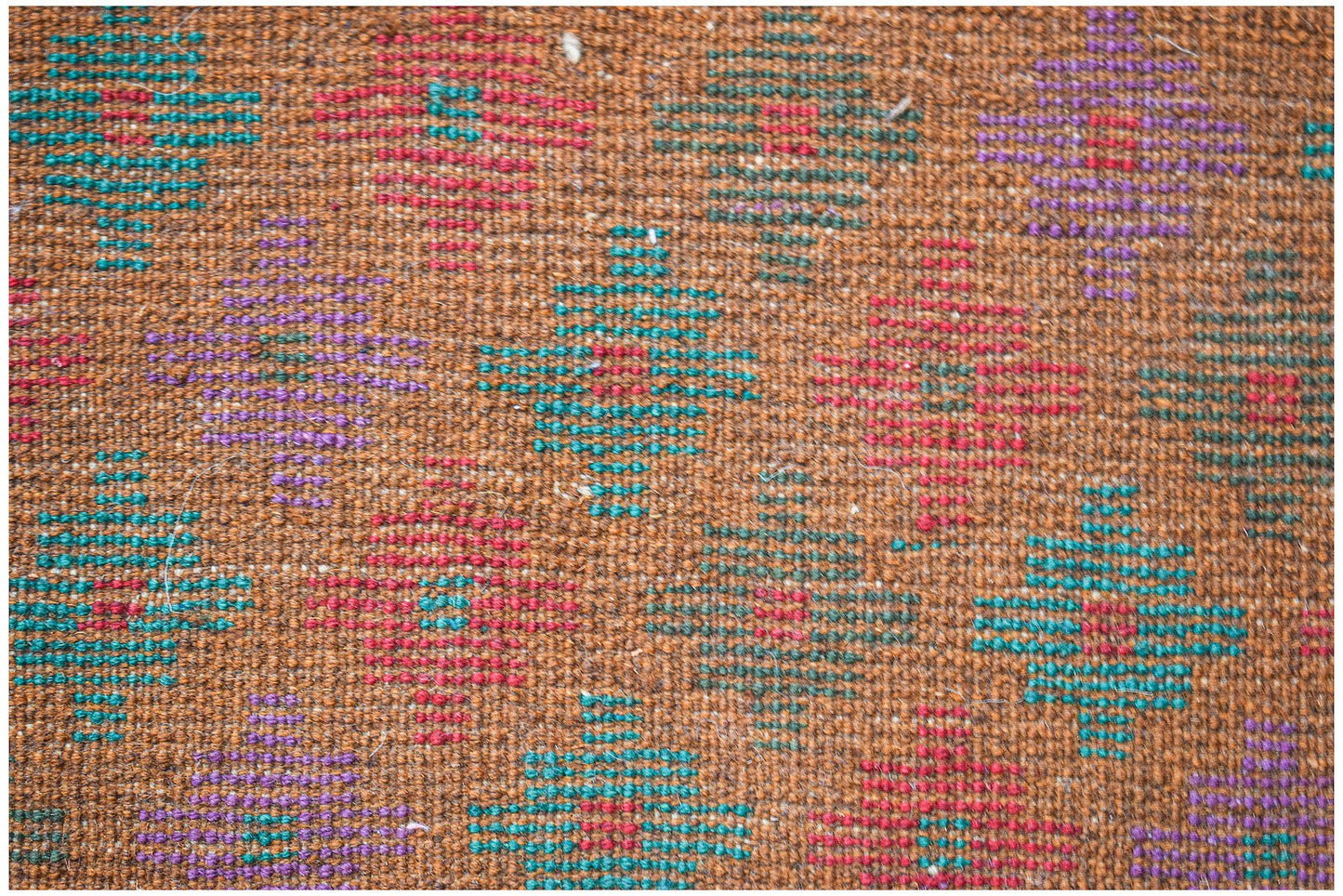 Handmade Afghan Pashm rug featuring a geometric diamond pattern in red, blue, and purple on brown.
