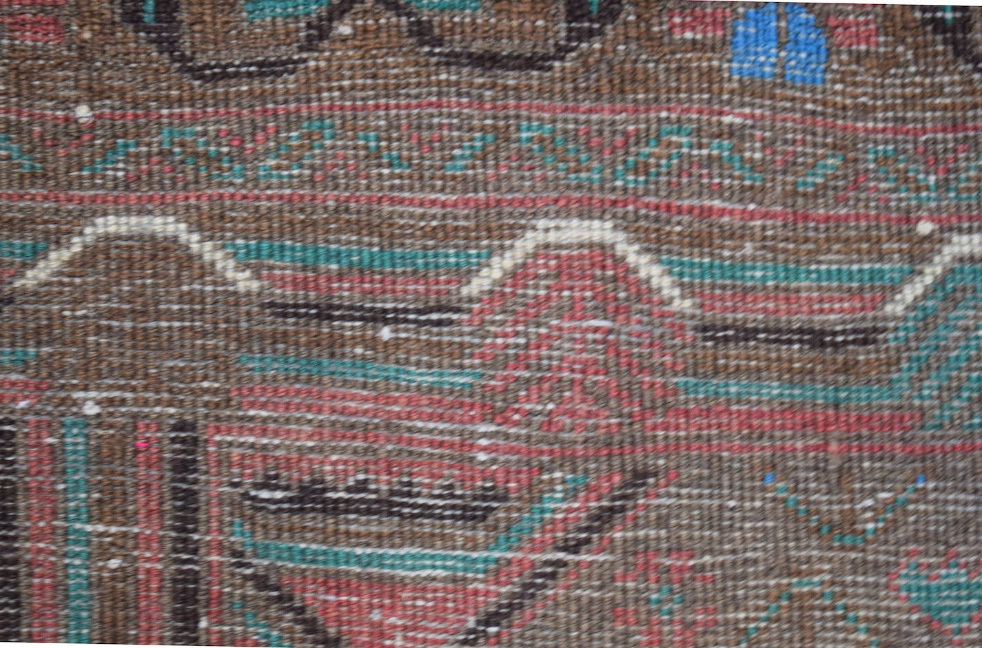 A handmade Afghan Pashm rug featuring a tribal pattern in dark red, brown, blue, and ivory tones.
