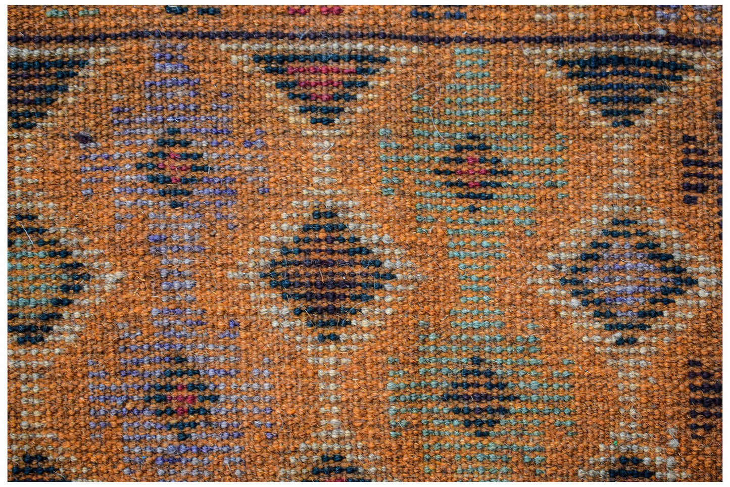 Handmade Afghan wool rug featuring a geometric diamond pattern in earthy orange and dark tones.