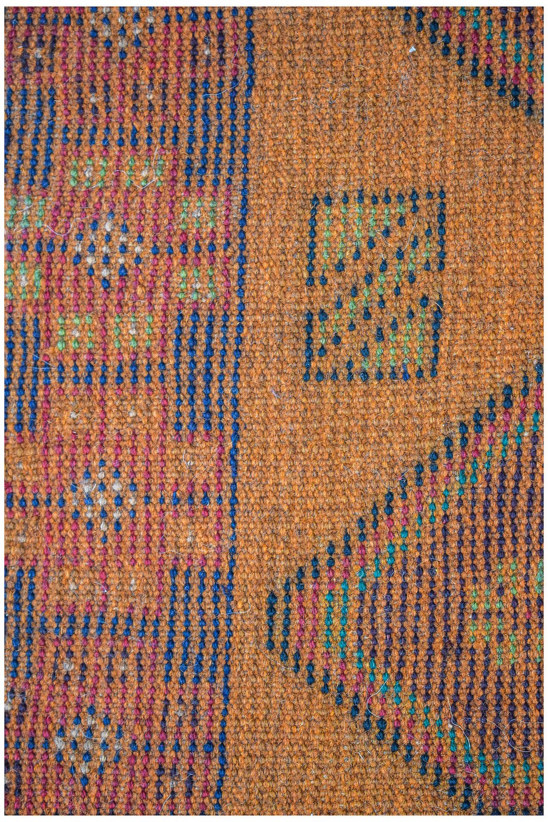 Handmade Afghan Pashm rug featuring a geometric pattern in blue, green, and red on an orange base.