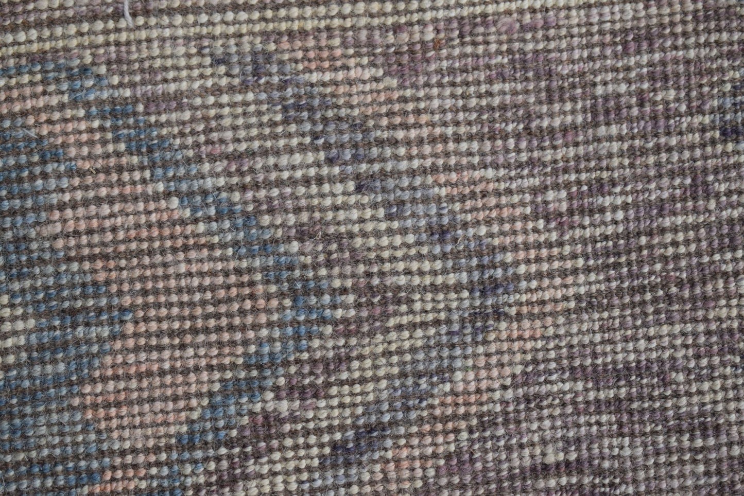 A close-up view of a handmade Afghan Pashm rug featuring a textured, woven wool pattern.