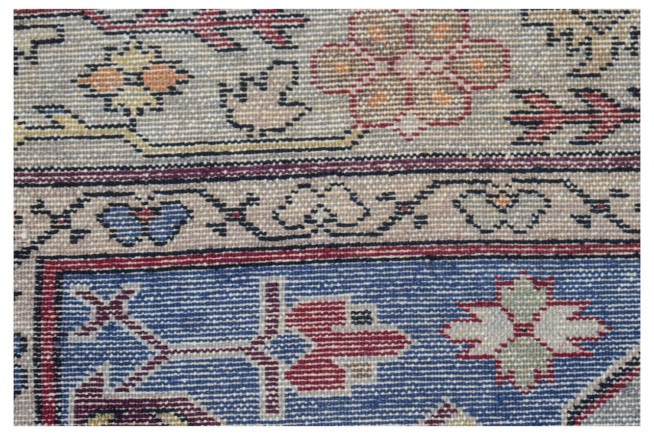 Vintage Caucasian rug with floral and geometric patterns in blue, red, and beige.