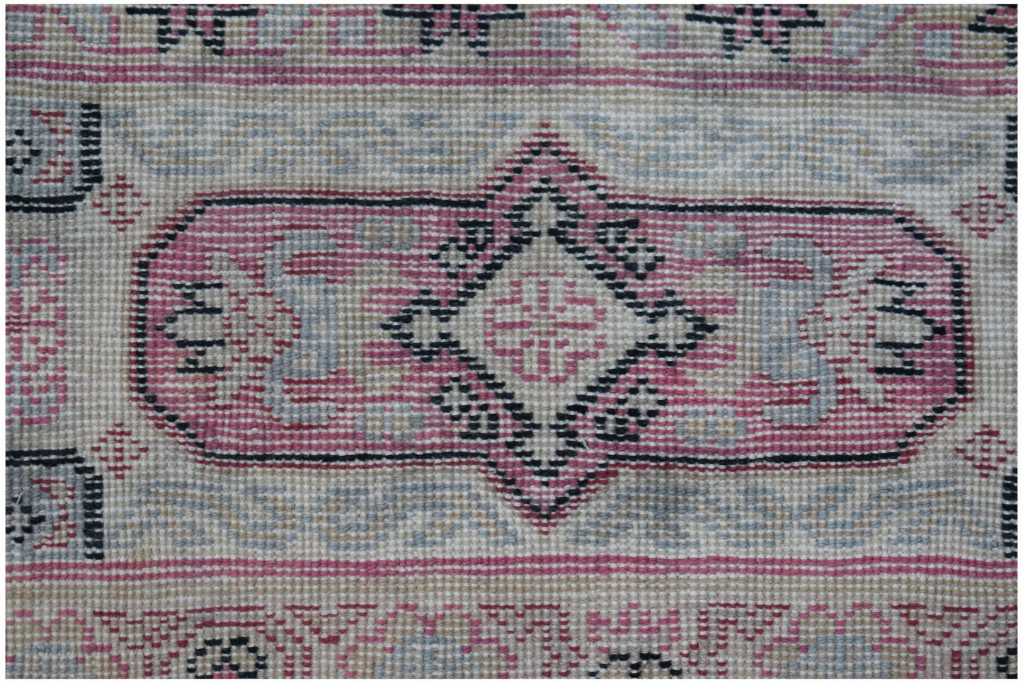A vintage handwoven Chinese rug featuring a pink and grey geometric medallion pattern.