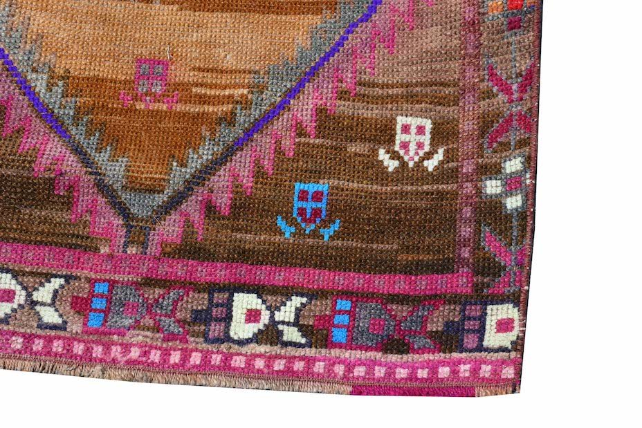 Vintage Kurdish Herki runner with tribal motifs in brown, pink, and blue.