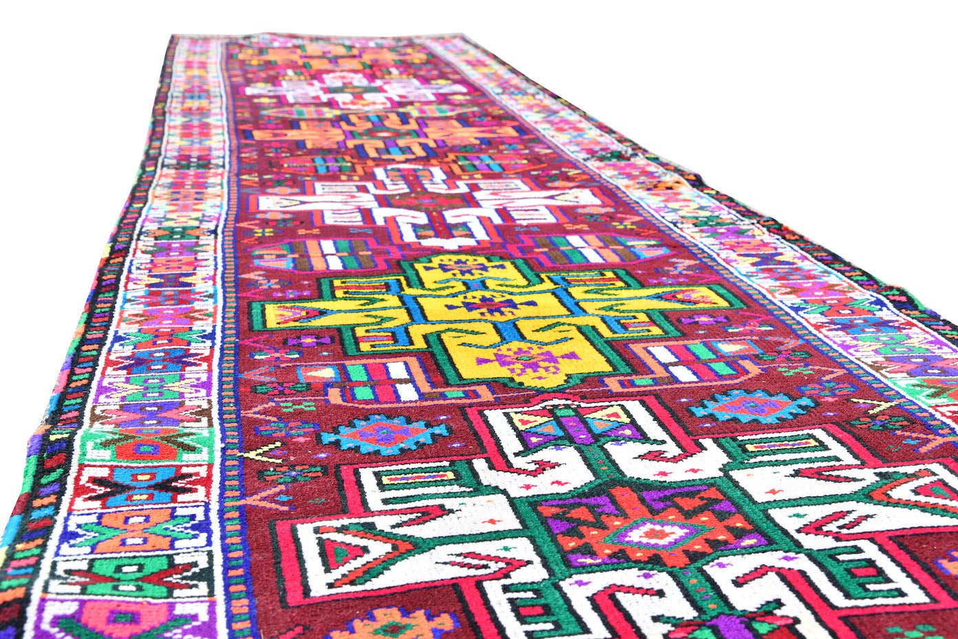 A vintage Kurdish Herki runner featuring vibrant tribal motifs in wool and nylon on a red base.