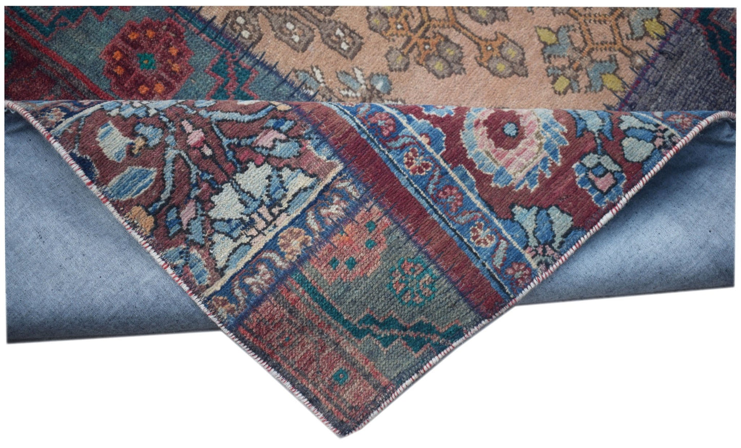 A vintage patchwork runner with intricate floral patterns in blue, red, and beige wool.