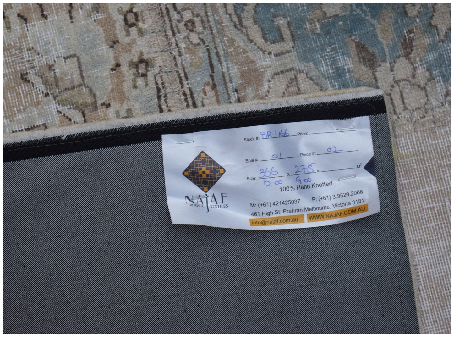 The underside of a vintage patchwork rug features a white label with product details.