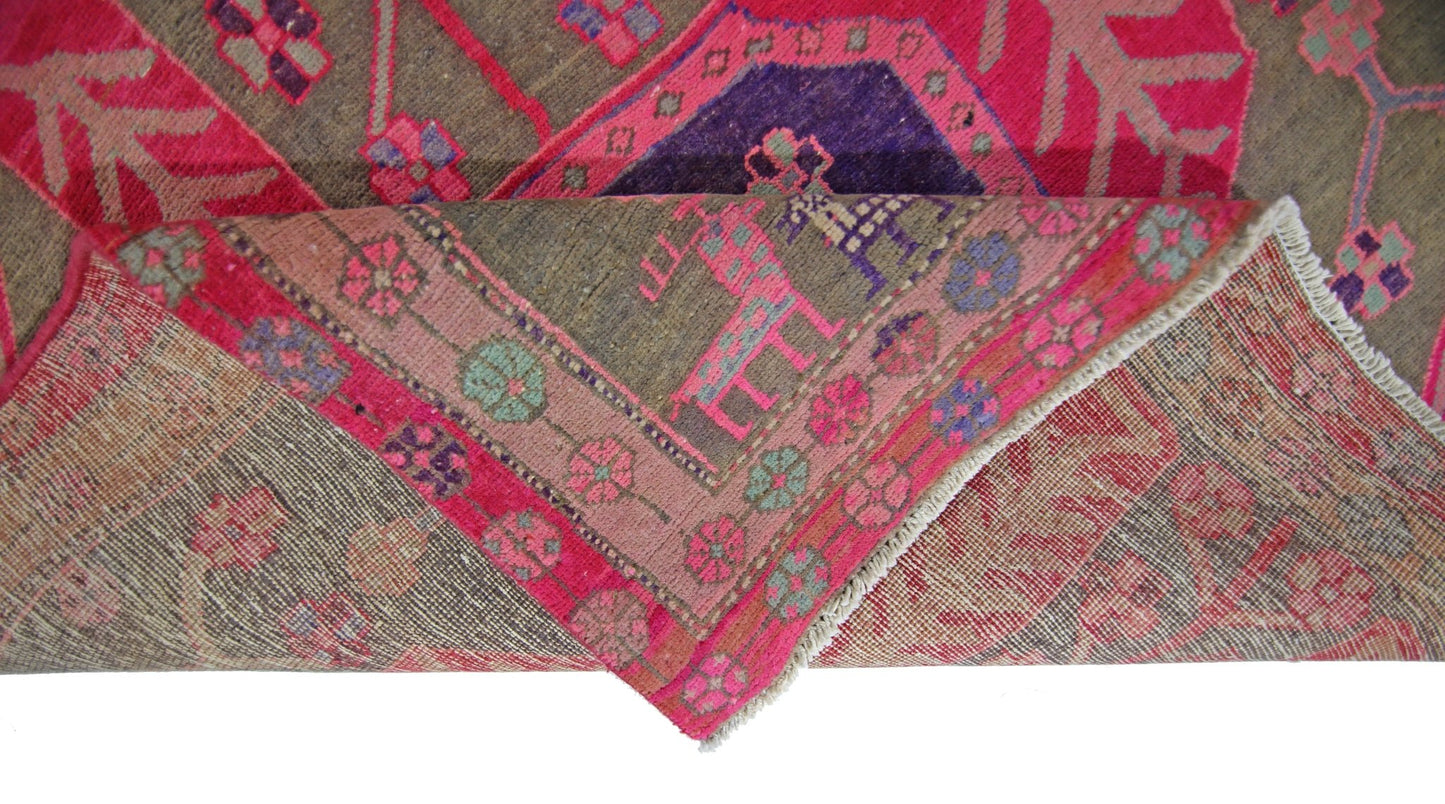 A vintage Persian Ardabil rug with a folded corner revealing its intricate floral pattern.