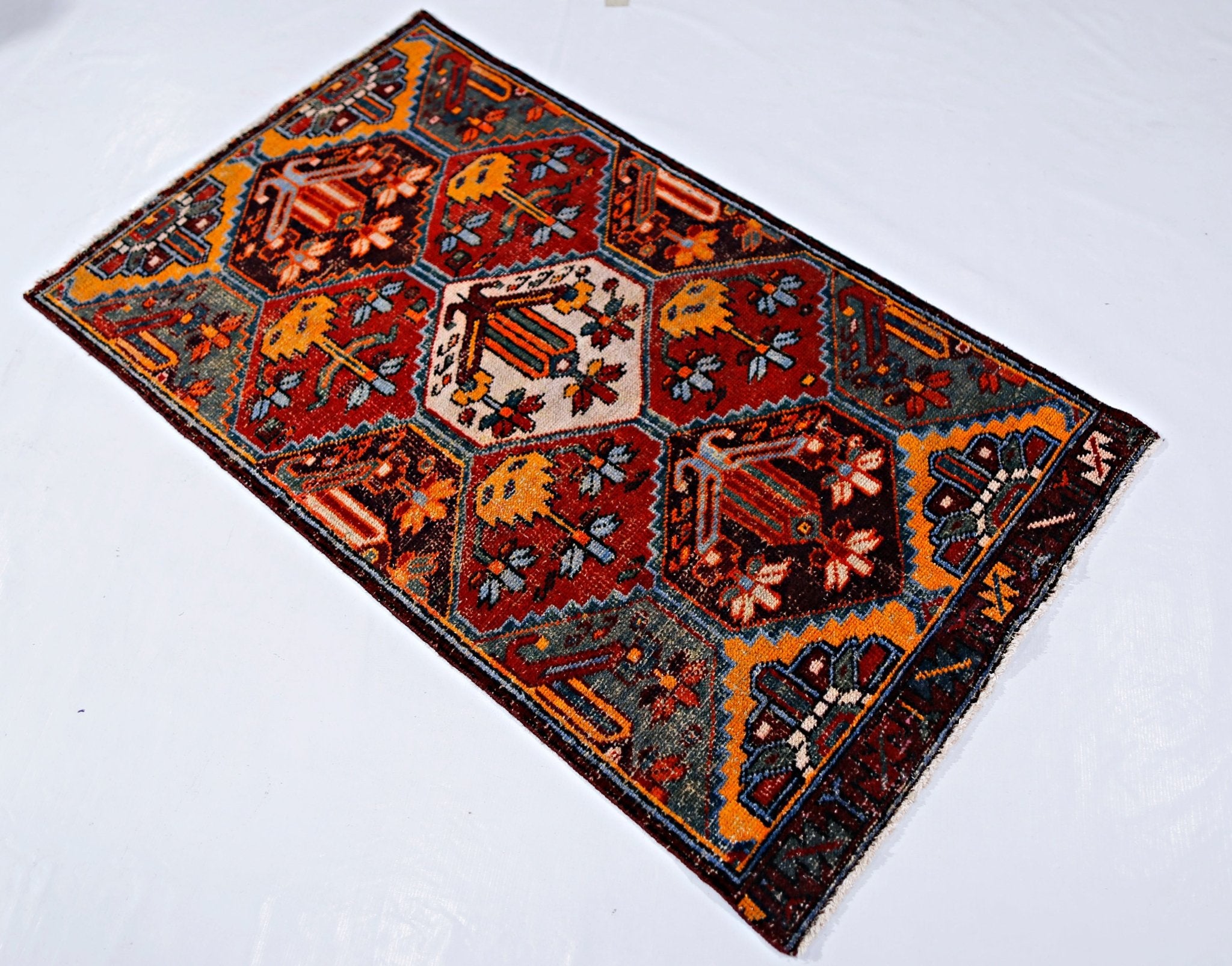 A vintage Persian Bakhtiari rug featuring a geometric hexagonal pattern in red, blue, and gold.