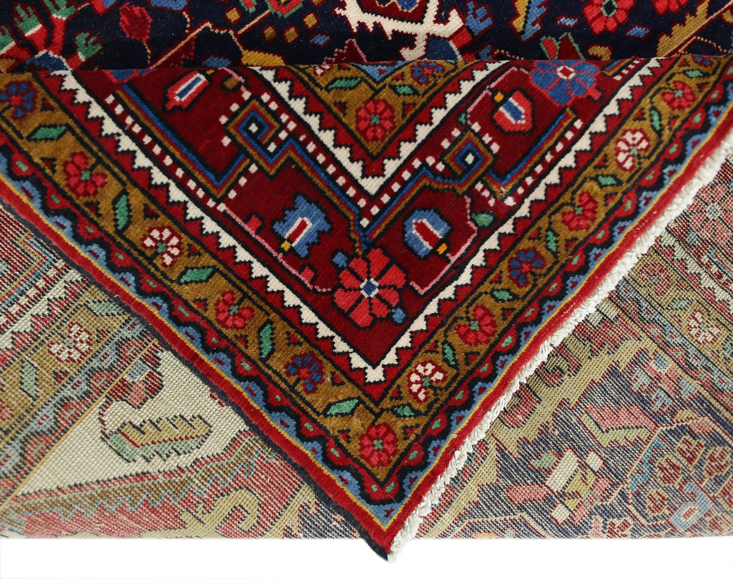 A folded vintage Persian Bakhtiari rug featuring intricate floral patterns in red, blue, and gold.