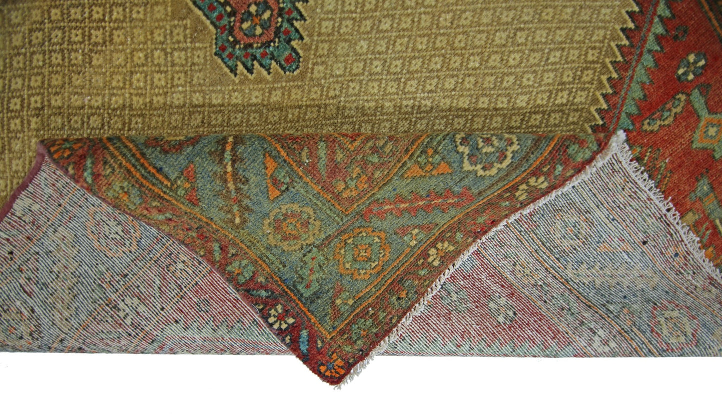 A corner of a vintage Persian Bibikabad rug is folded back to show its wool pile and cotton base.