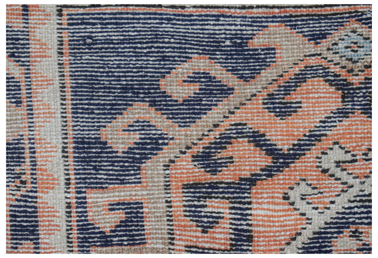 Close-up of a handwoven vintage Persian runner with navy blue, coral, and beige geometric patterns.