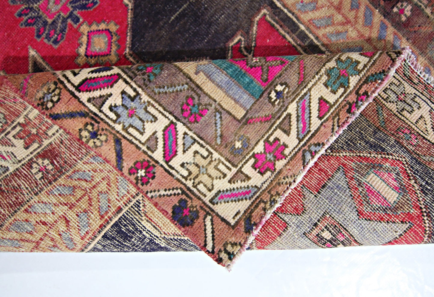 A folded vintage Persian Hamadan runner featuring intricate geometric patterns in vibrant colors.