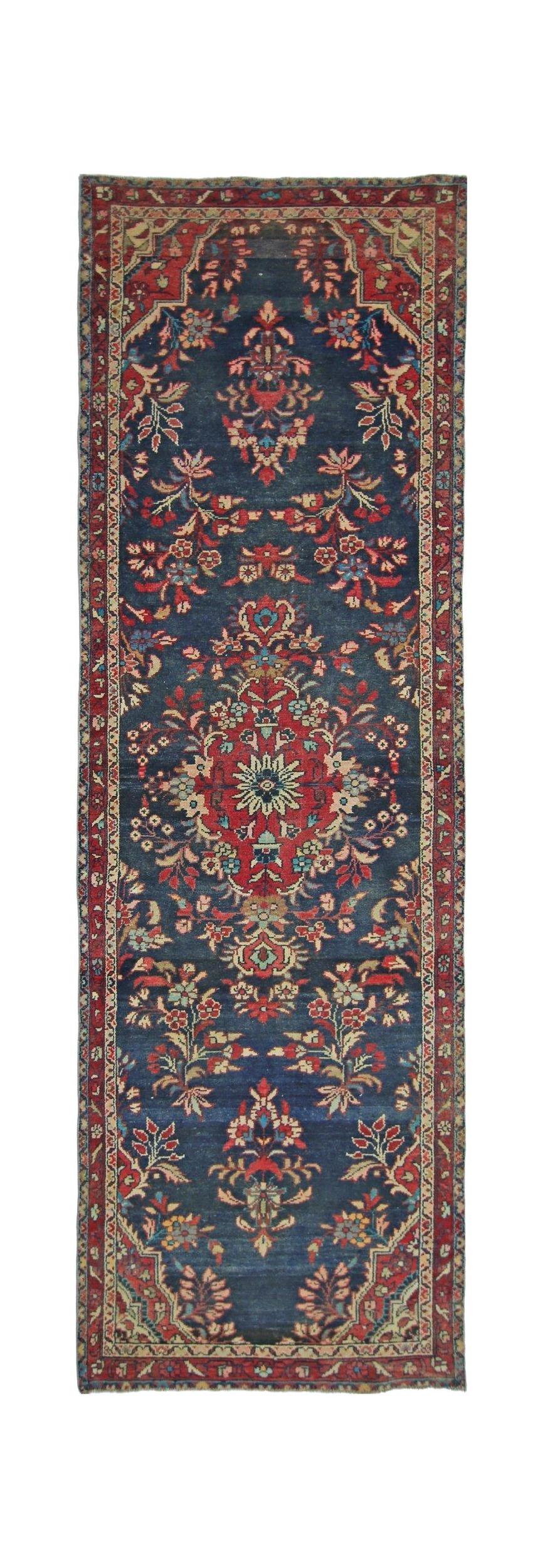A vintage Persian Sarouk runner featuring a floral medallion pattern on a deep blue wool field.