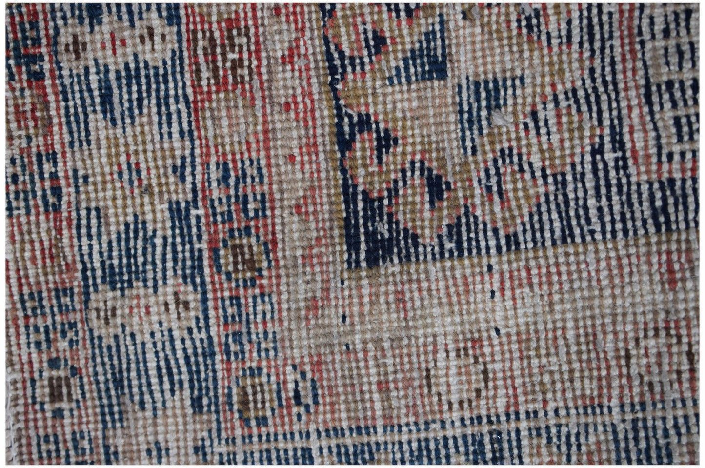 A close-up of a vintage handwoven Persian runner featuring a geometric pattern in red and blue.