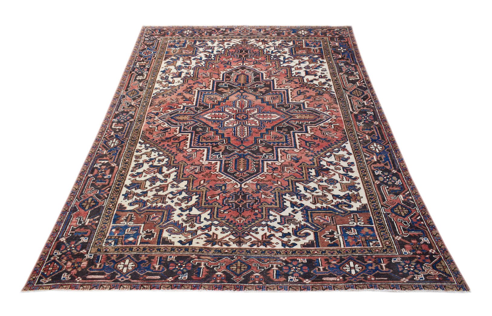 A vintage handwoven Persian Heriz rug featuring a geometric medallion in red, blue, and cream.