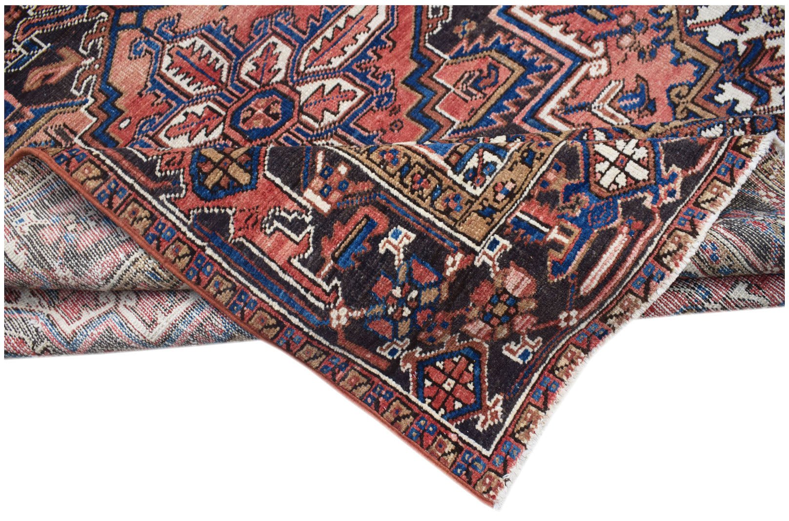 A vintage handwoven Persian Heriz rug featuring a geometric floral pattern in red and blue.