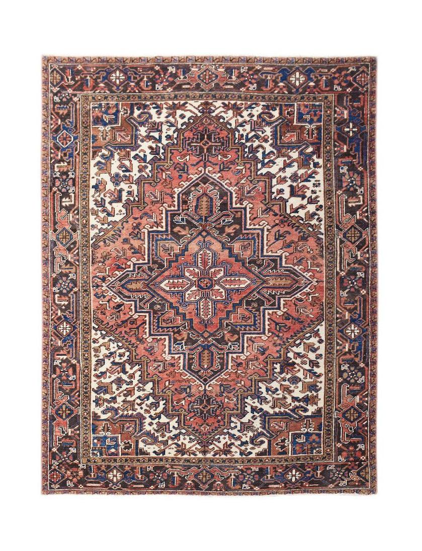 A vintage handwoven Persian Heriz rug featuring a geometric medallion on a rust and cream field.