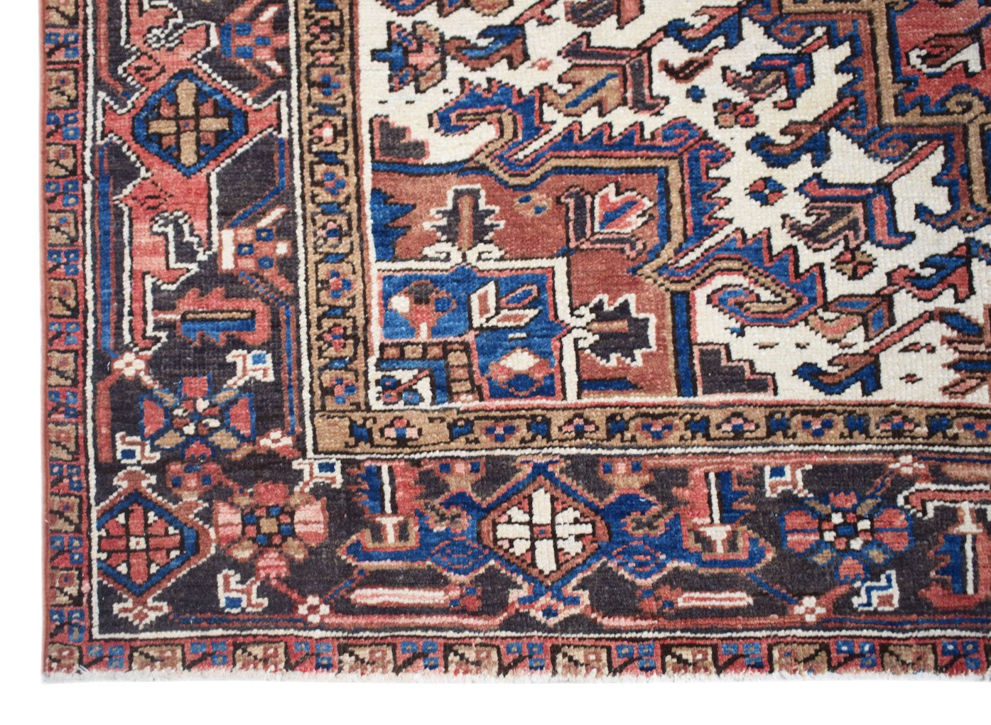A vintage Persian Heriz rug featuring a geometric pattern in shades of blue, red, and cream.
