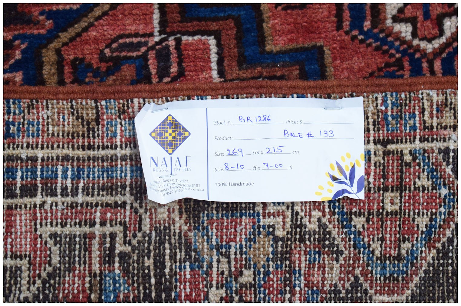 A vintage Persian Heriz rug with a geometric pattern in red, blue, and cream tones.