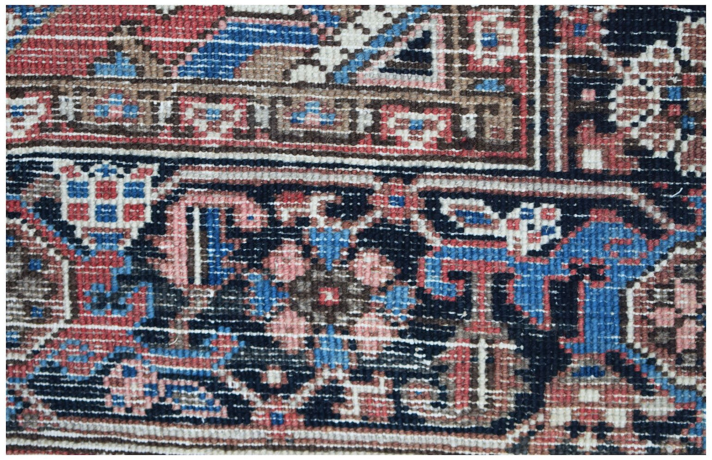 A close-up of a vintage Persian Heriz rug featuring intricate geometric patterns in red and blue.
