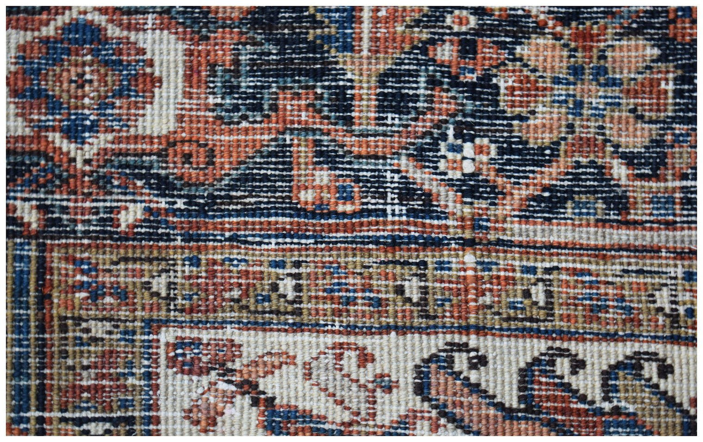 A close-up view of a vintage Persian Heriz rug featuring intricate geometric patterns in wool.