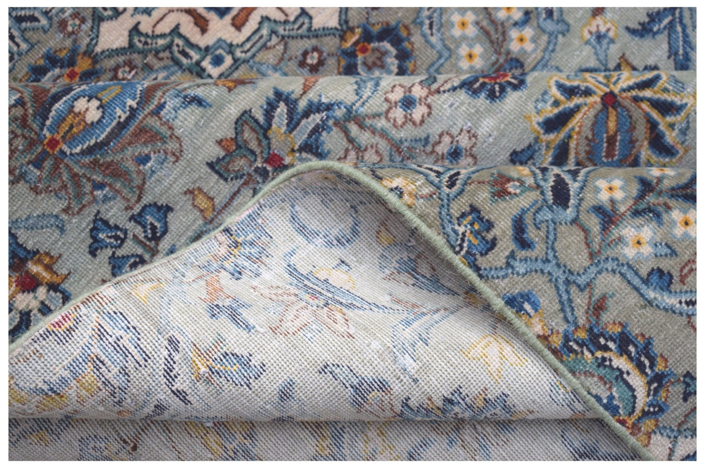 A vintage Persian Kashan rug featuring intricate floral patterns in blue and green tones.