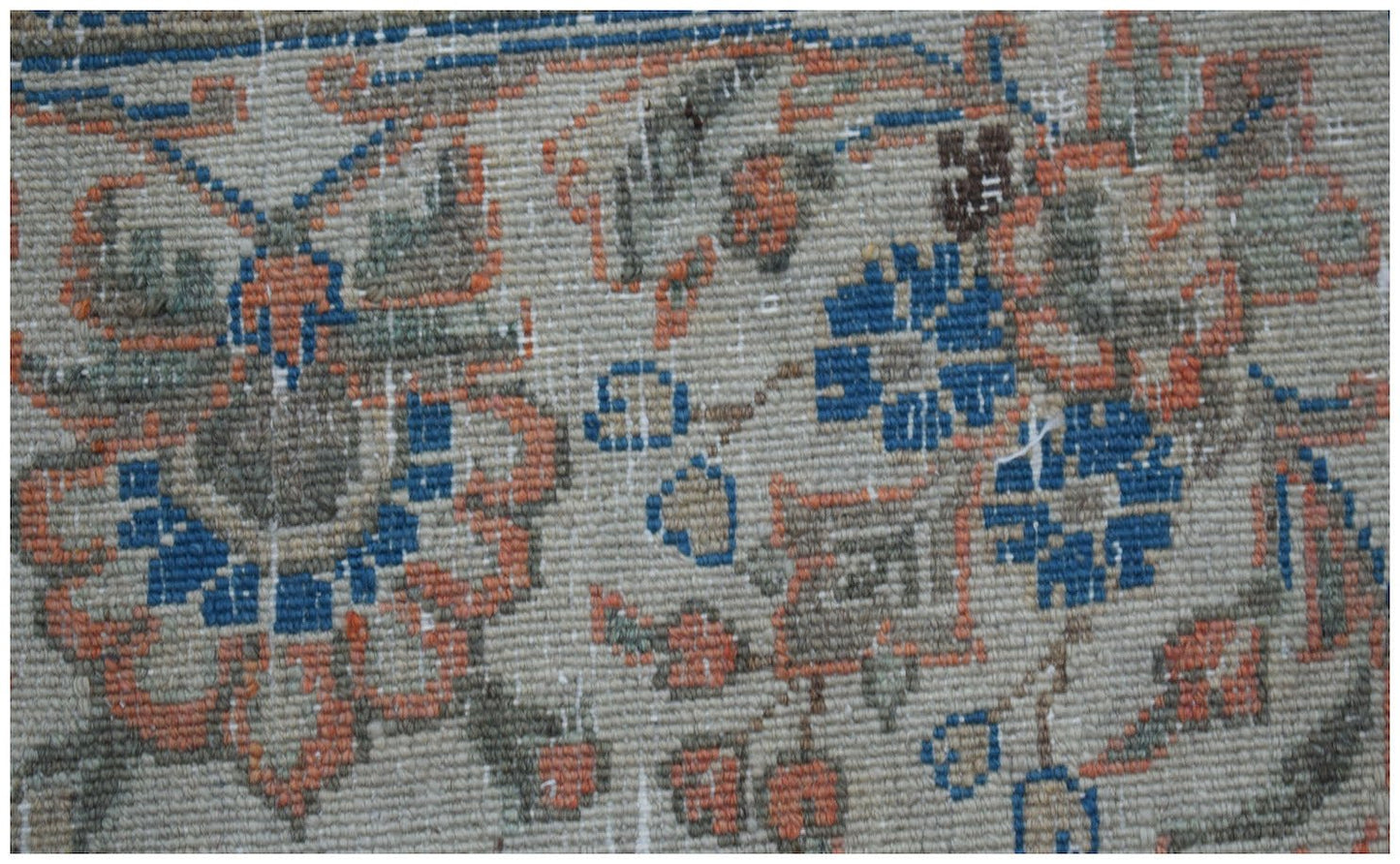 A close-up of a vintage Persian Kerman rug featuring intricate floral patterns in blue and orange.