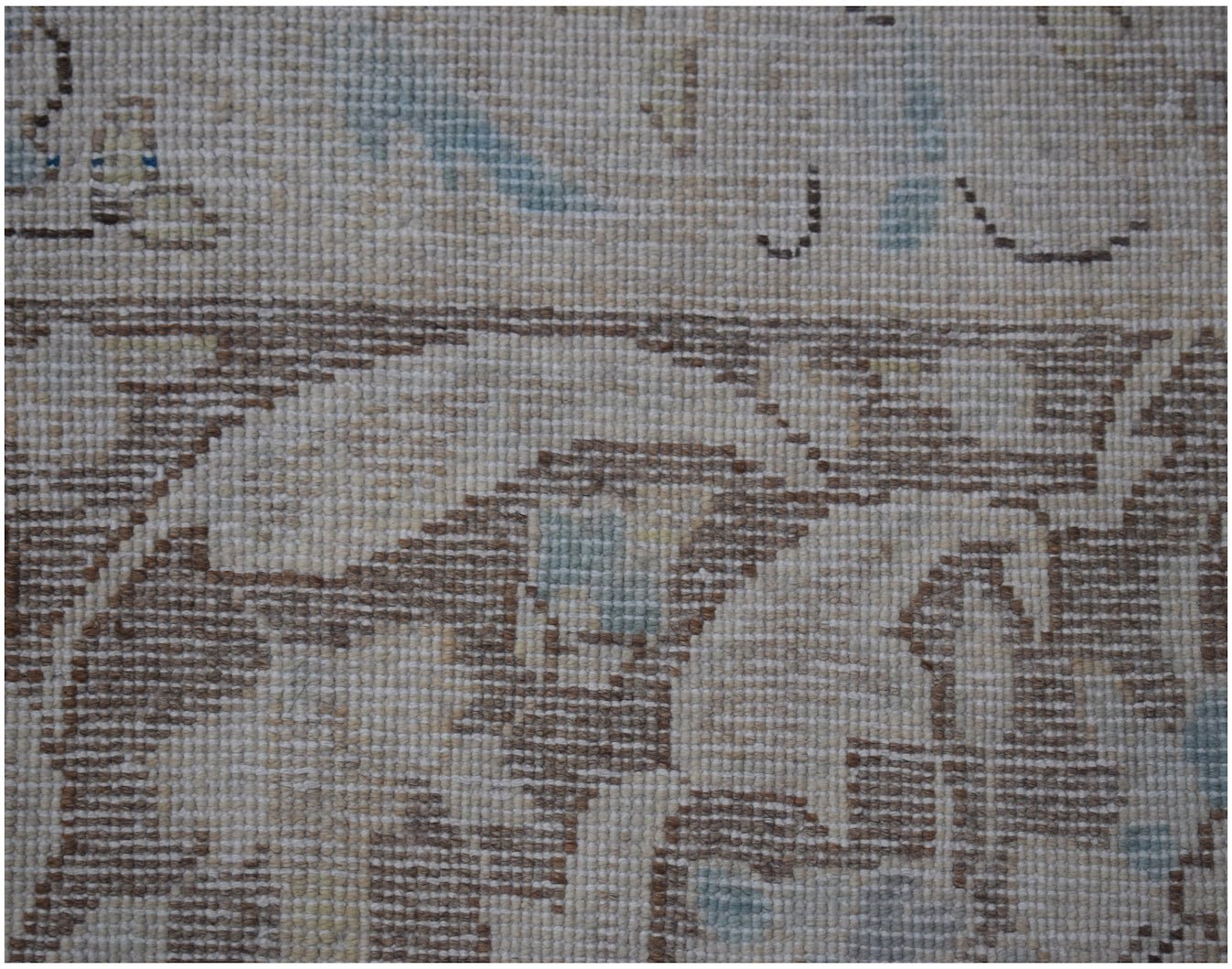 A close-up of a vintage Persian Kerman rug featuring intricate floral patterns in muted tones.