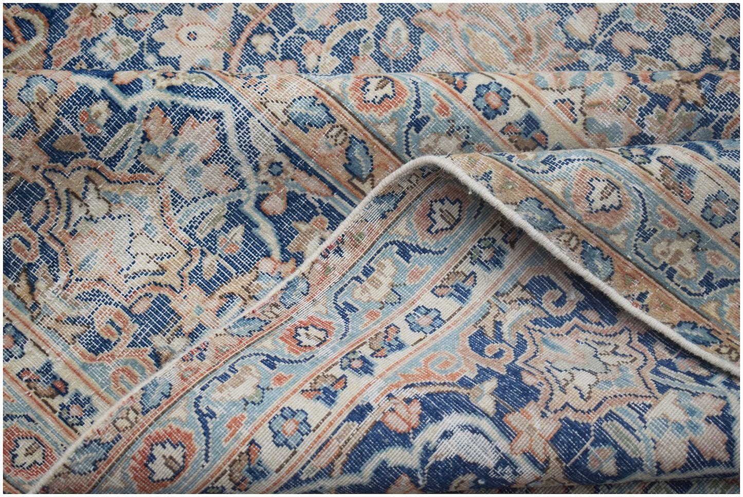 A vintage Persian Kerman rug featuring an intricate floral medallion design in blue and peach tones.