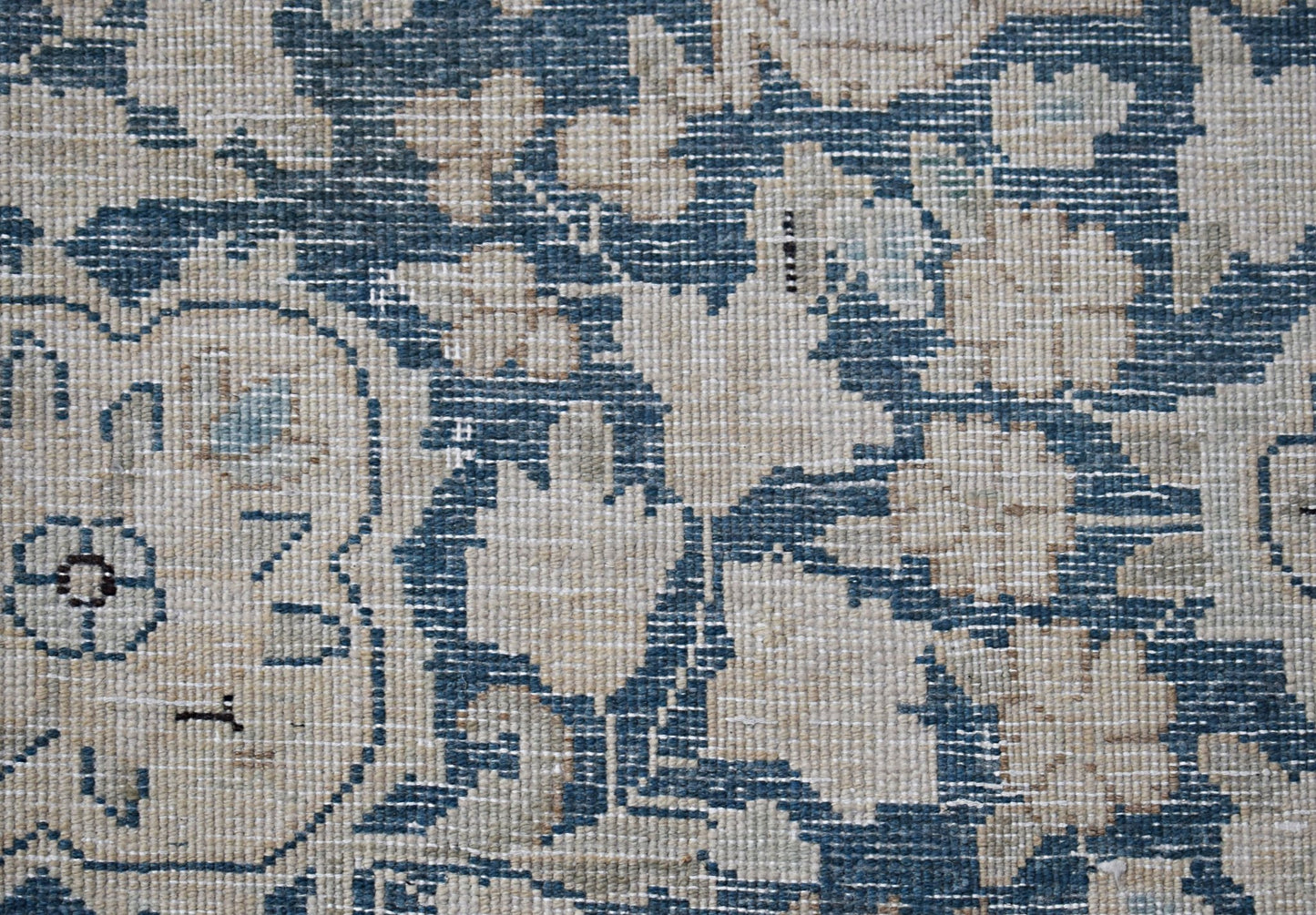 A close-up of a vintage Persian Kerman rug featuring intricate blue and cream floral patterns.