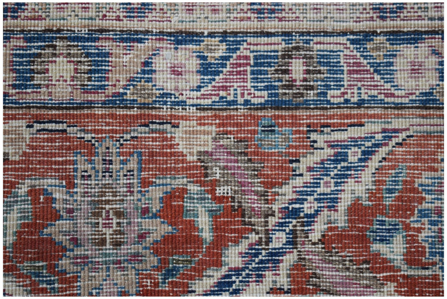 A close-up of a vintage Persian Mashhad rug featuring intricate floral patterns in red and blue.