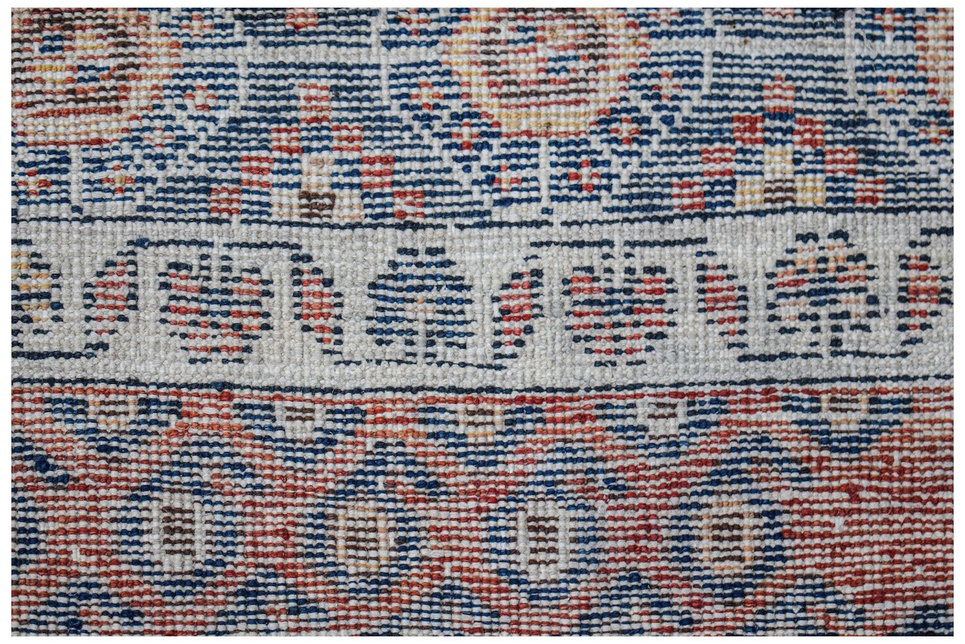 A close-up of a vintage handwoven Persian rug featuring intricate blue and red geometric patterns.