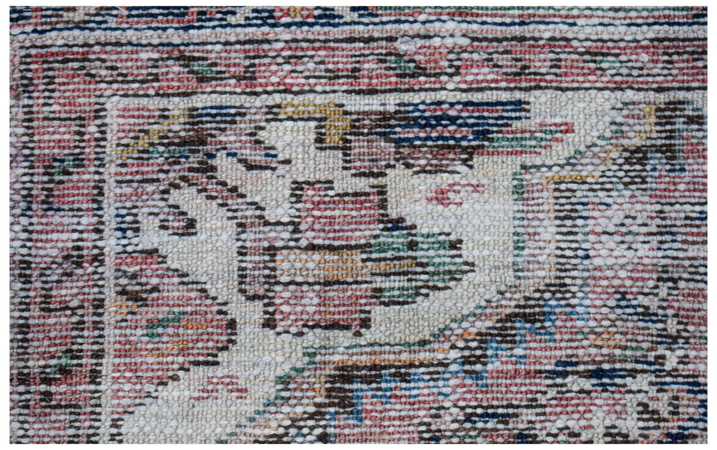A close-up of a vintage handwoven Persian rug featuring intricate geometric patterns in wool.