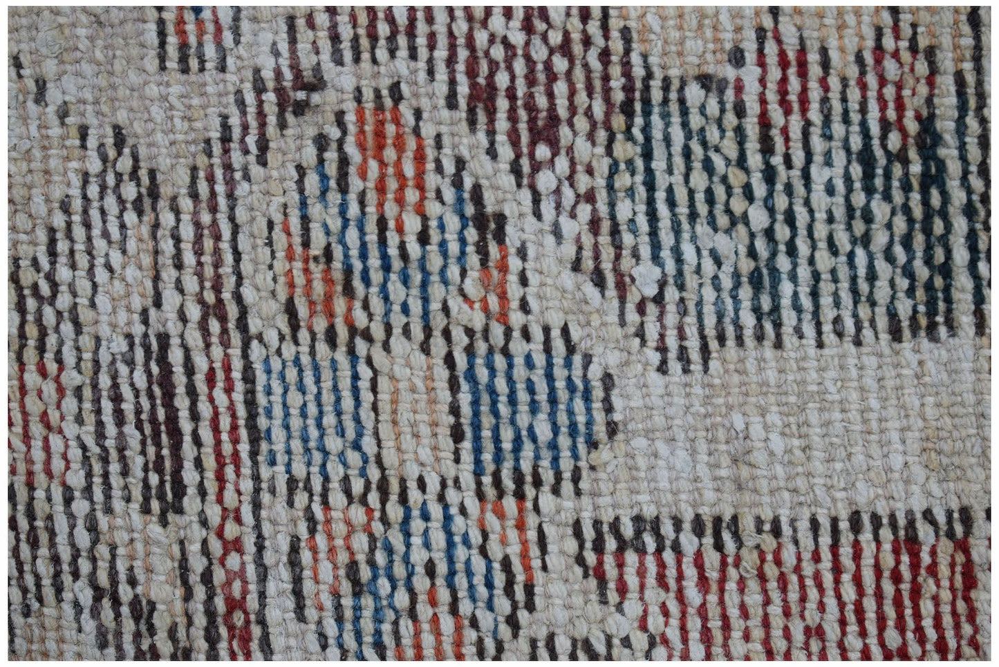 Close-up of a vintage handwoven Persian rug with a textured weave and geometric patterns in red, blue, and brown.