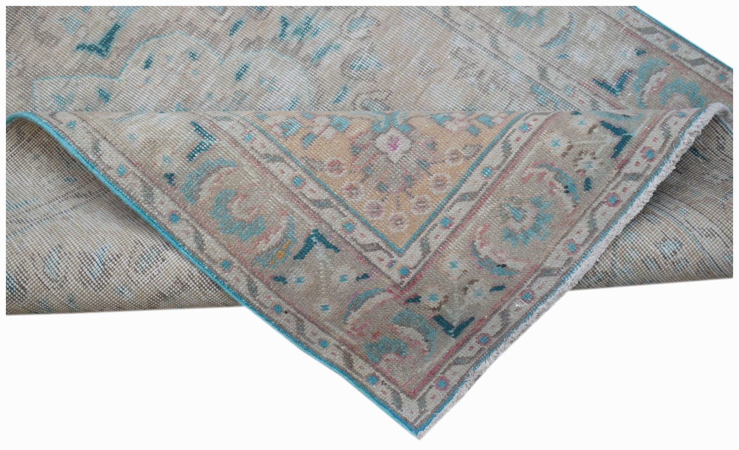 A handwoven vintage Persian rug featuring a faded floral pattern in beige, blue, and pink tones.