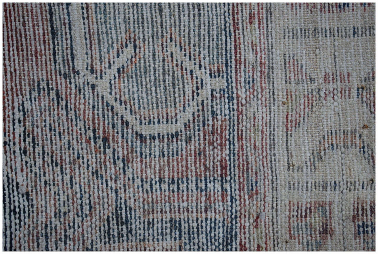 A close-up of a handwoven vintage Persian rug featuring a faded geometric pattern in wool.
