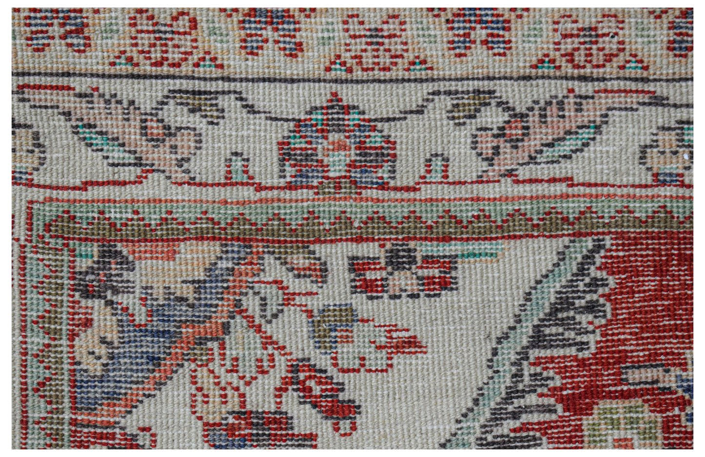 Close-up of a vintage Persian rug with intricate floral and geometric patterns in red, blue, and green.