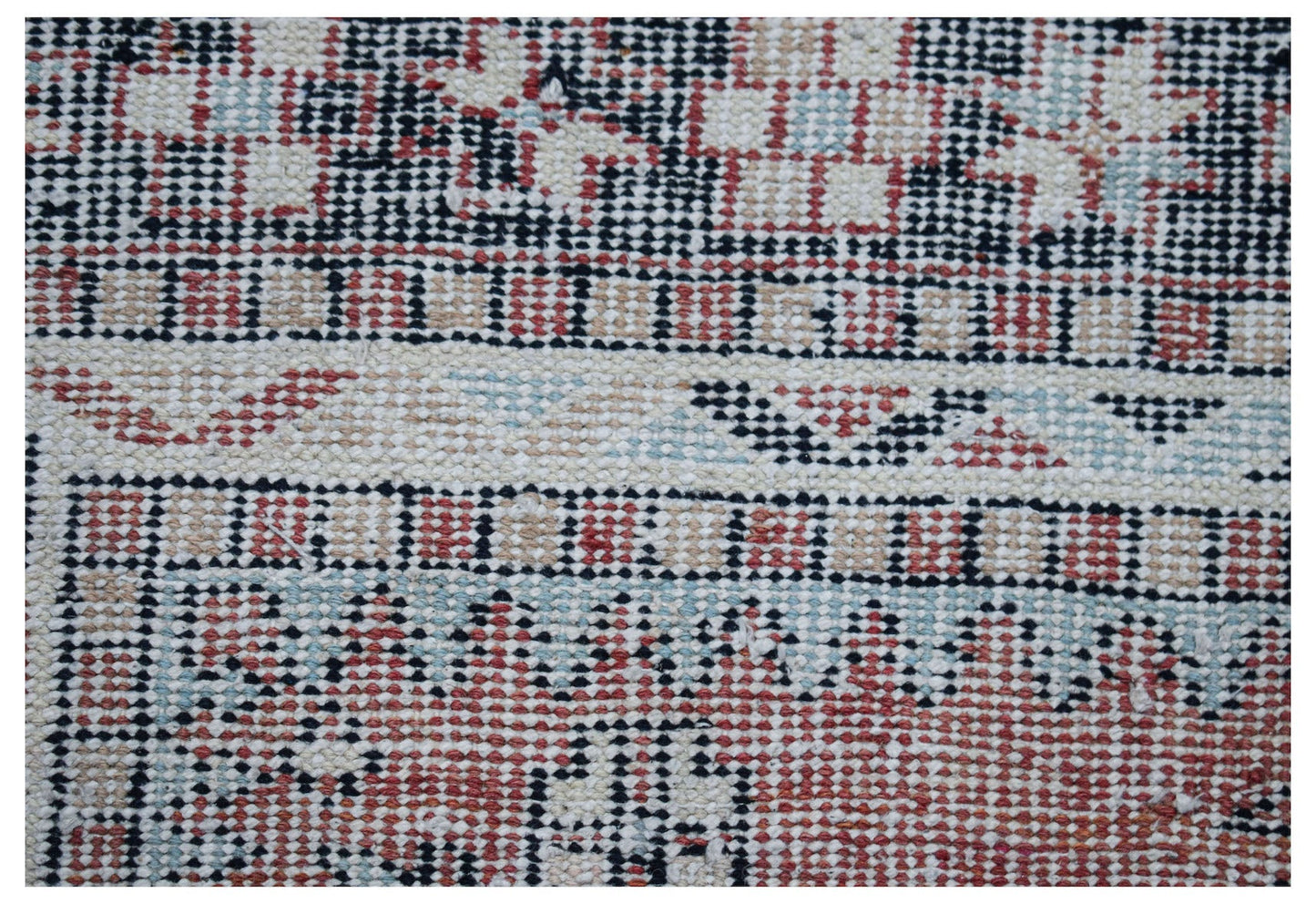 A close-up of a handwoven vintage Persian rug featuring a geometric pattern in red, blue, and cream.