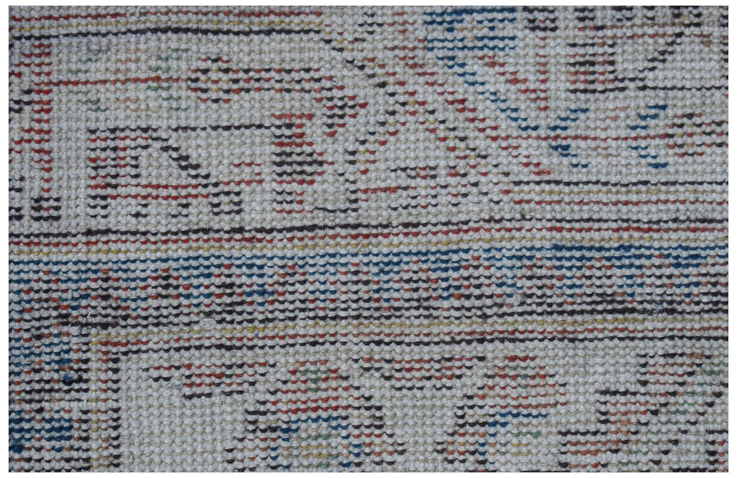 Vintage Persian rug with a woven pattern in red, blue, and black on a cream background.