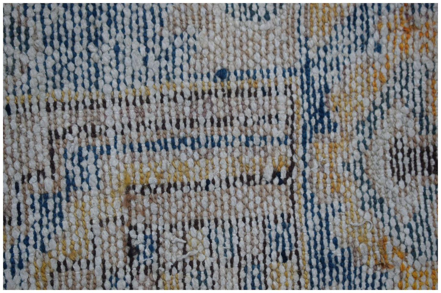 A close-up view of a handwoven vintage Persian rug featuring a distressed blue and yellow pattern.