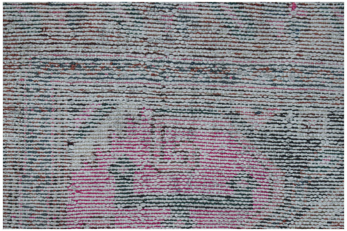 A close-up of a vintage handwoven Persian rug featuring a distressed pattern in pink and grey.