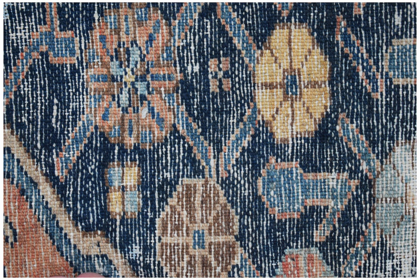 A close-up of a vintage Persian rug featuring floral patterns in blue, yellow, and orange tones.